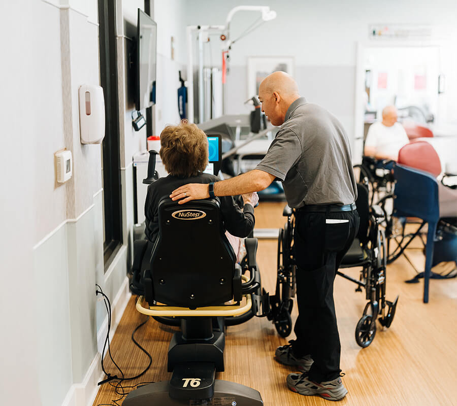 Senior and physical therapist using stationary bike