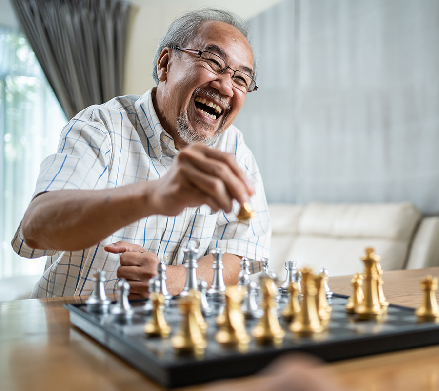 Smiling senior playing chess in a bright living room, enjoying the game.