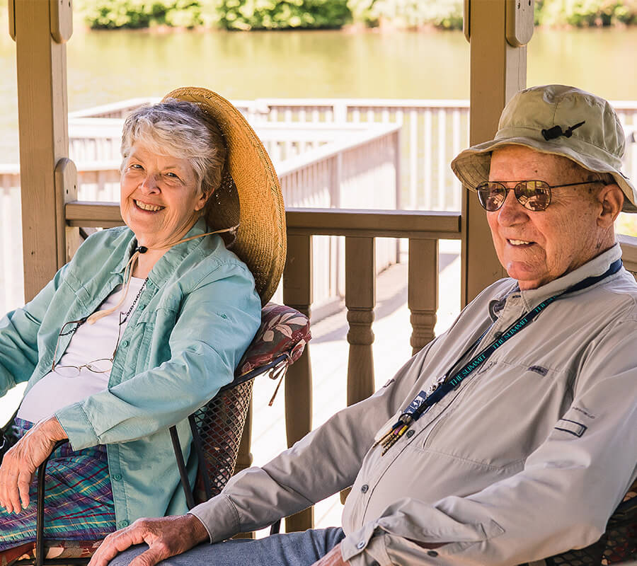 Senior couple smiling on a porch near a lake
