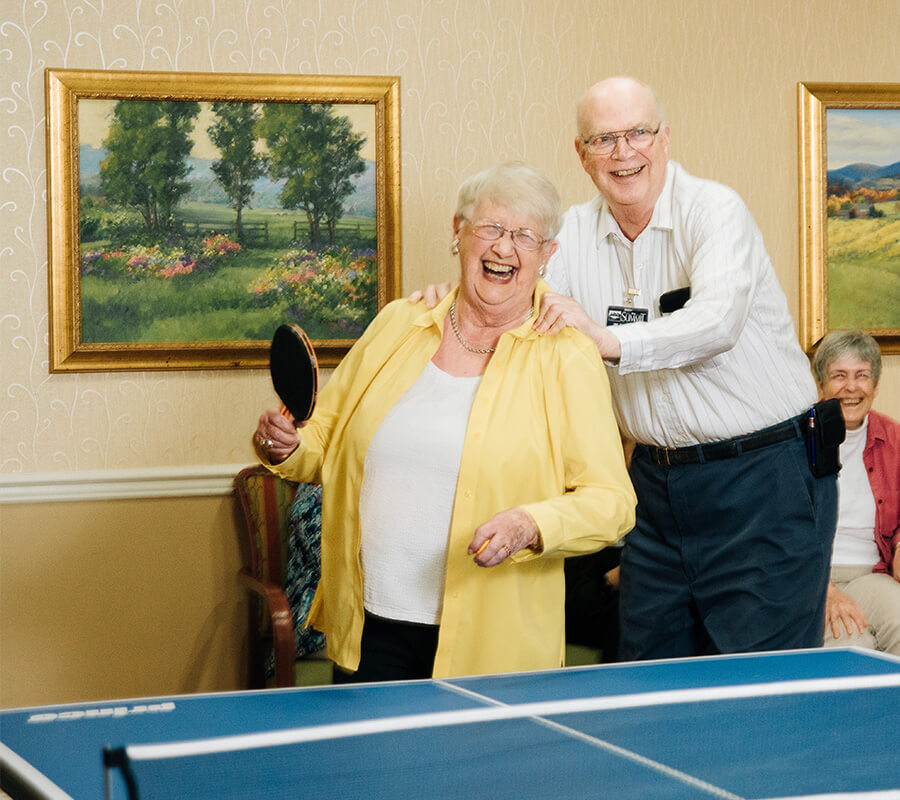 Senior couple laughing and preparing for a game of ping pong