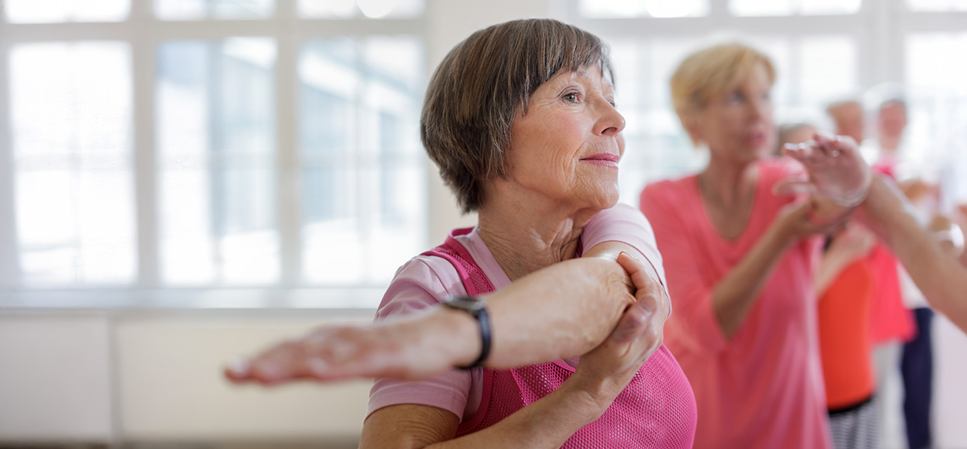 Seniors participating in a group fitness with light-filled windows.