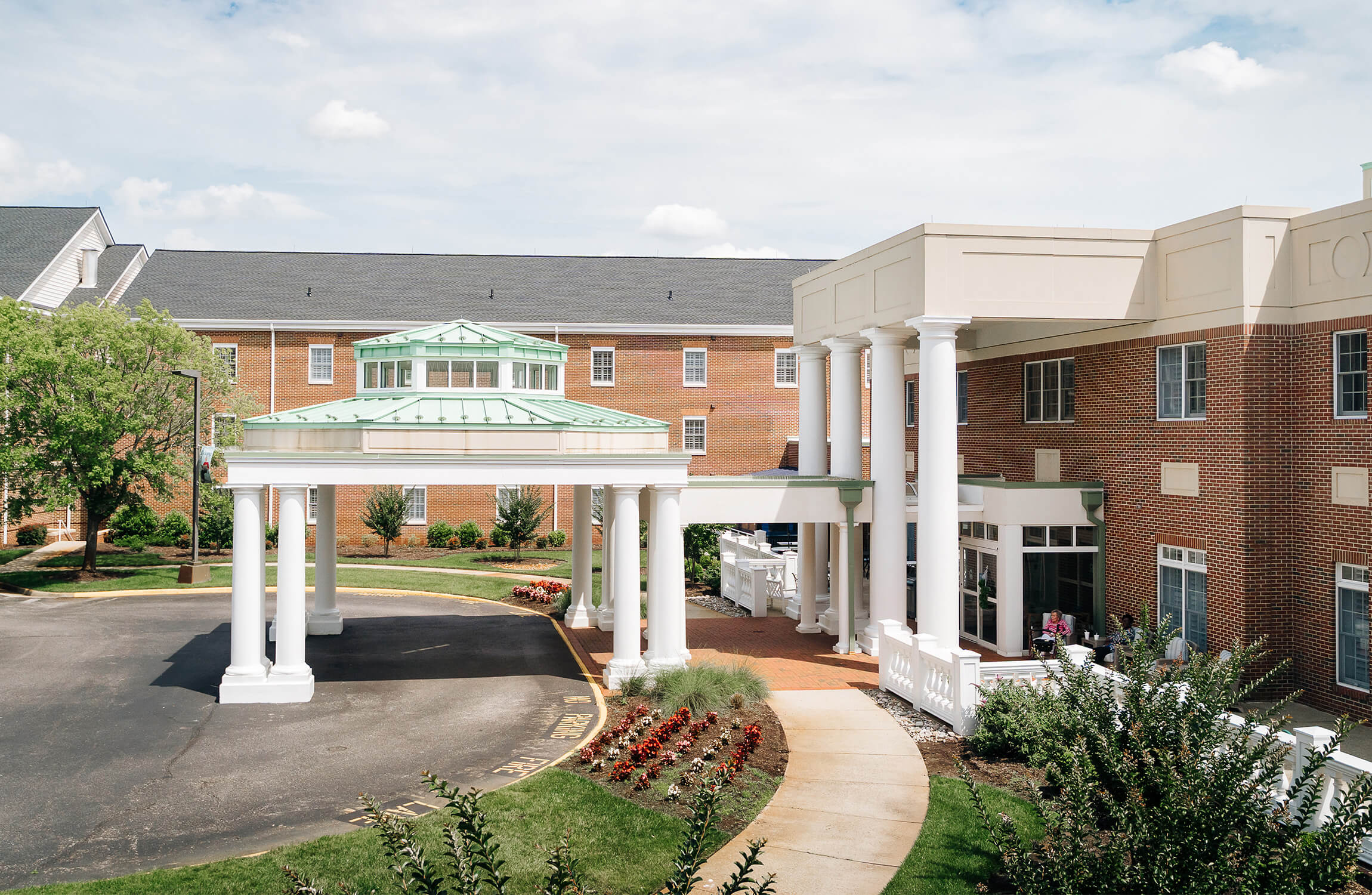 Senior Living Community Entrance Fountain and landscaped garden in front of a brick senior living community building.