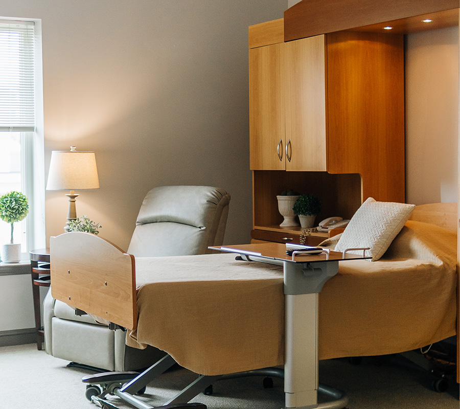 Comfortable unit with bed, recliner, and wood cabinetry in senior living community.