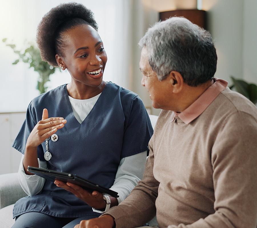 Senior man sits on couch to discuss care plan with nurse