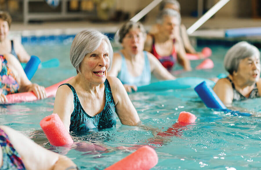Engaging Water Aerobics Class for Seniors Seniors participating in a water aerobics with pool noodles.