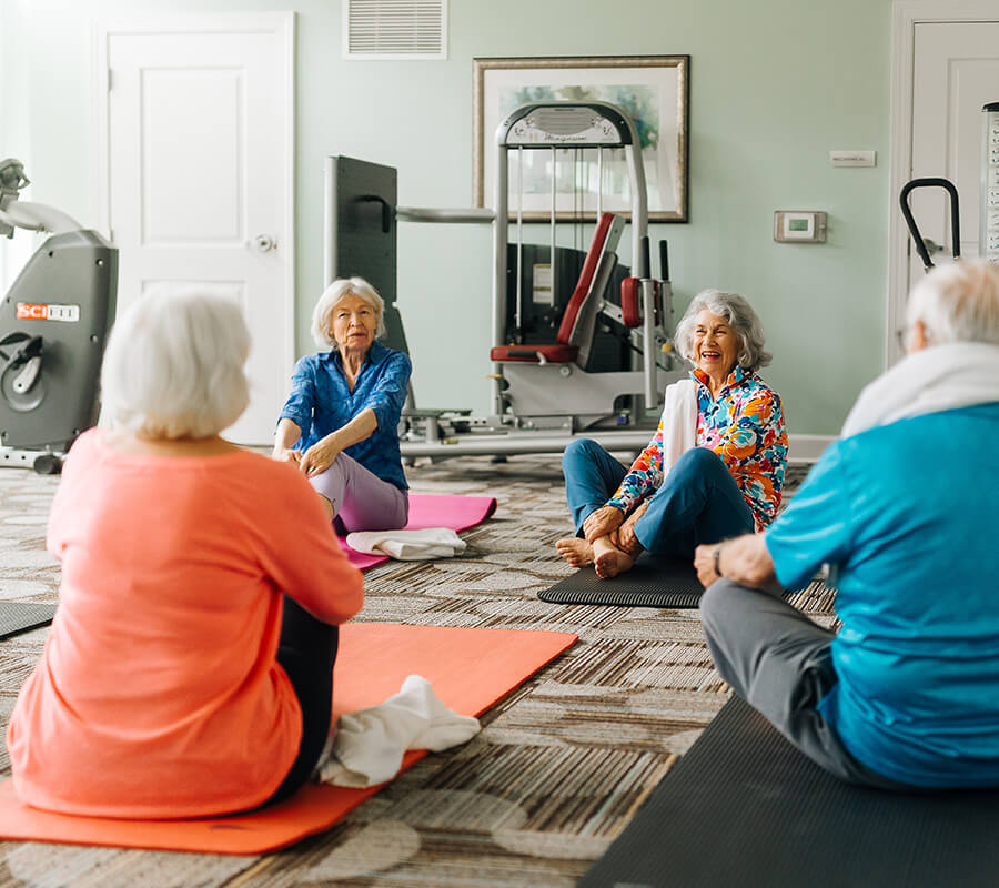 Seniors sit on yoga mats for class