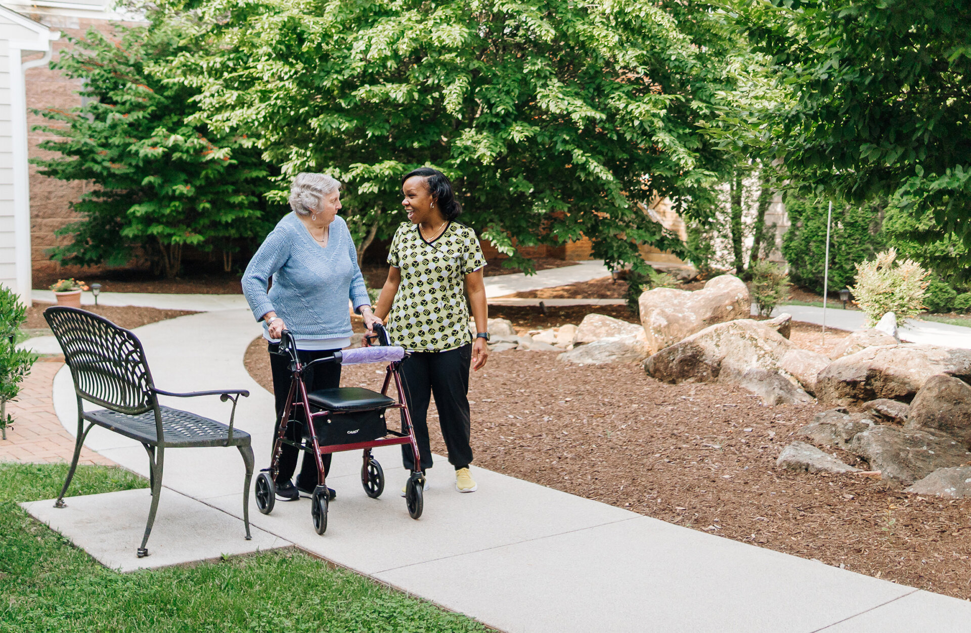 senior-woman-and-caregiver-walkig Senior resident of The Summit and caregiver taking a walk on a path