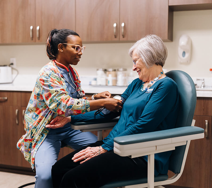 Healthcare professional checks senior womans blood pressure in a clinic setting.