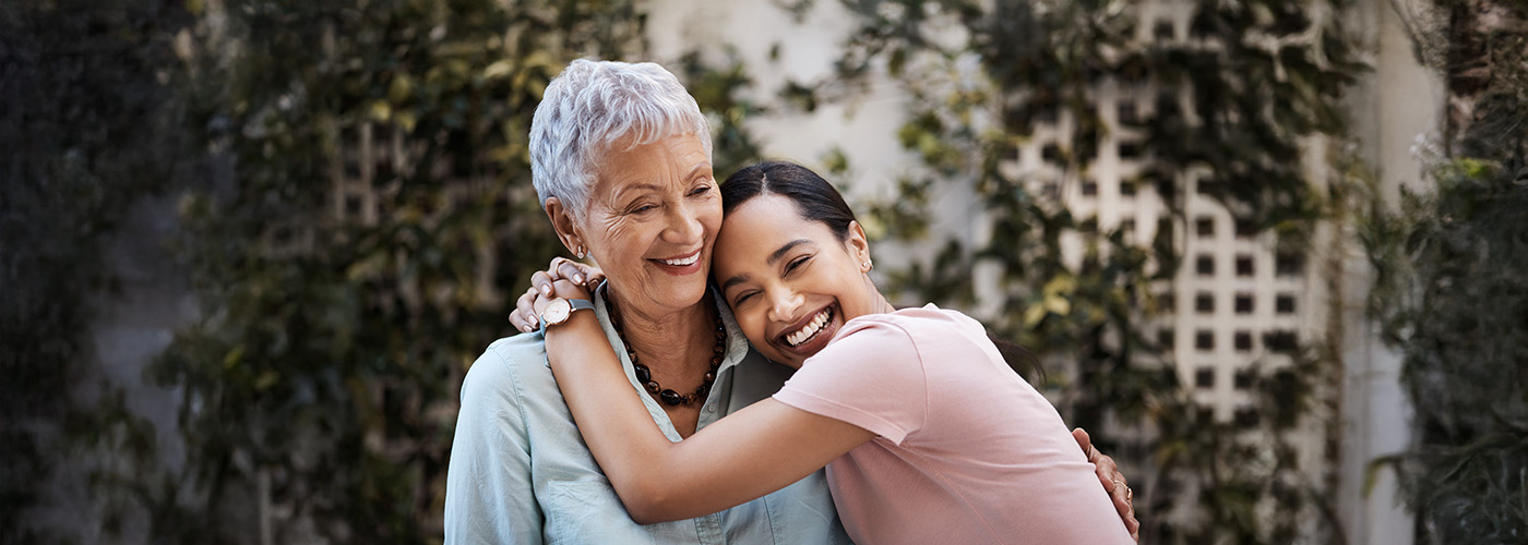 Adult daughter hugs elderly mother in garden