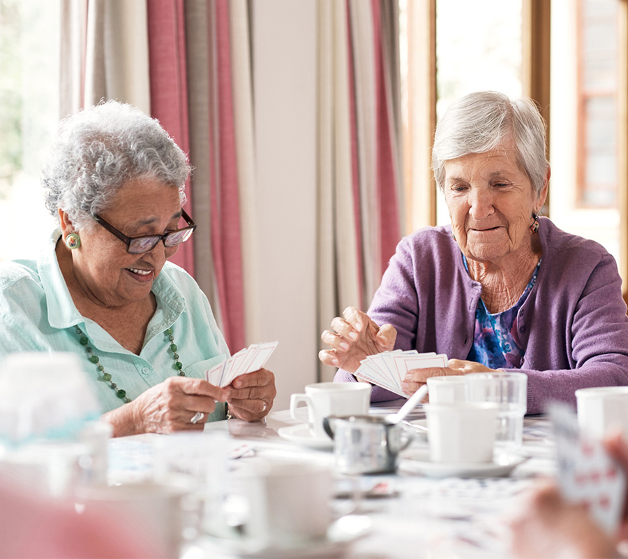 Two seniors enjoying a card game at a community dining area