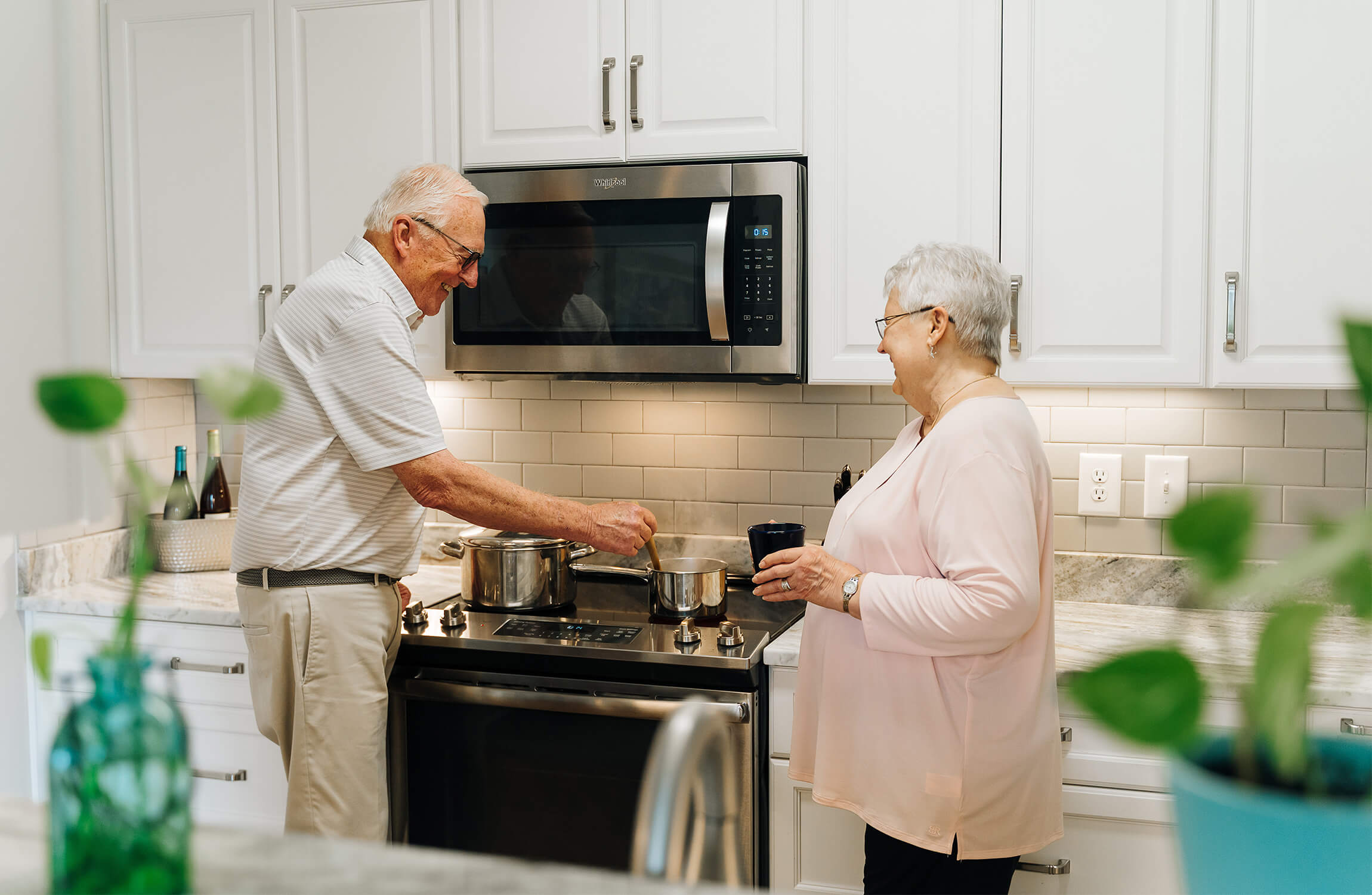 Two seniors enjoying cooking together in a modern kitchen.