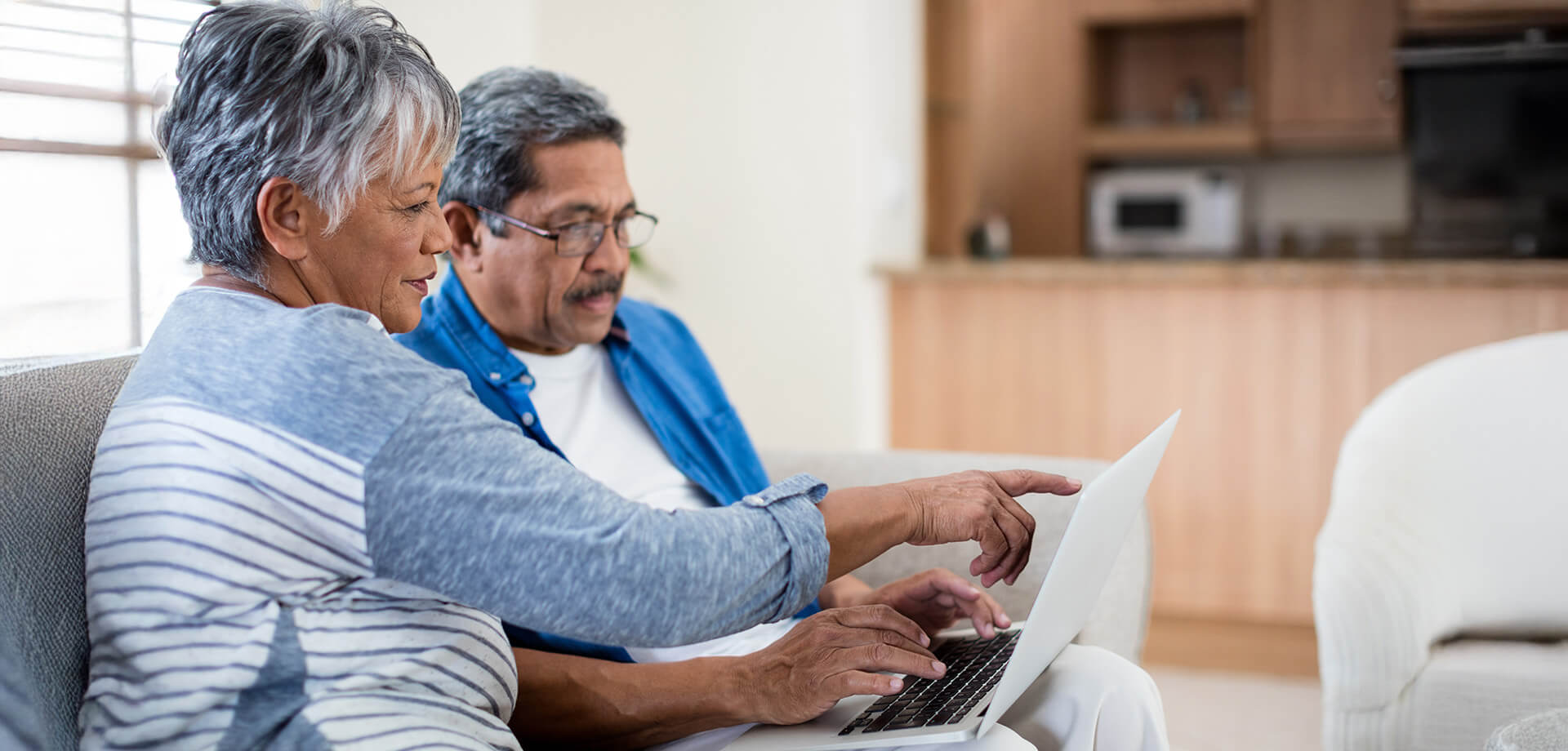 Senior couple using a laptop together on a comfortable couch.