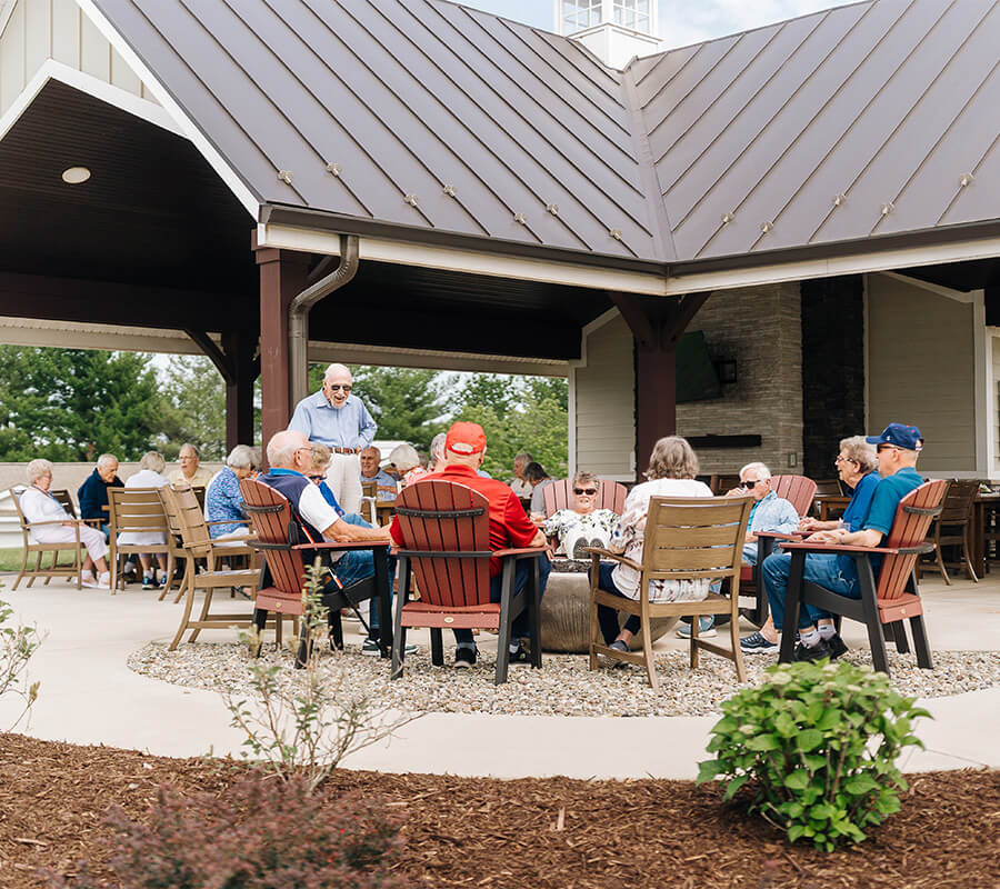 Senior friends sitting around firepit
