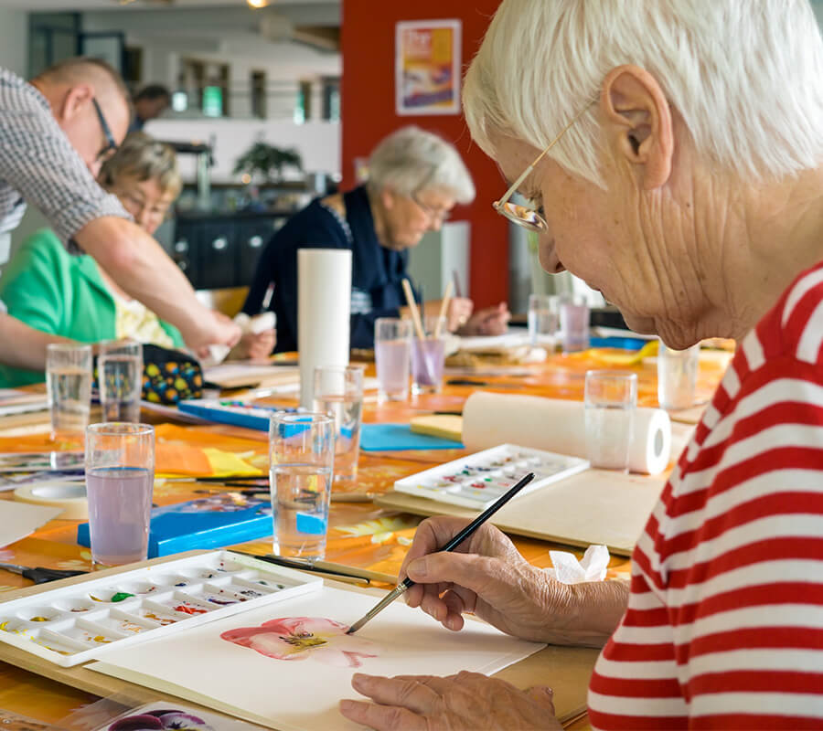 Seniors painting at a table in a community art class.