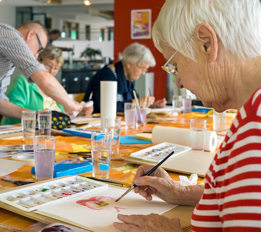 Seniors engaged in watercolor painting activity at a community workshop.