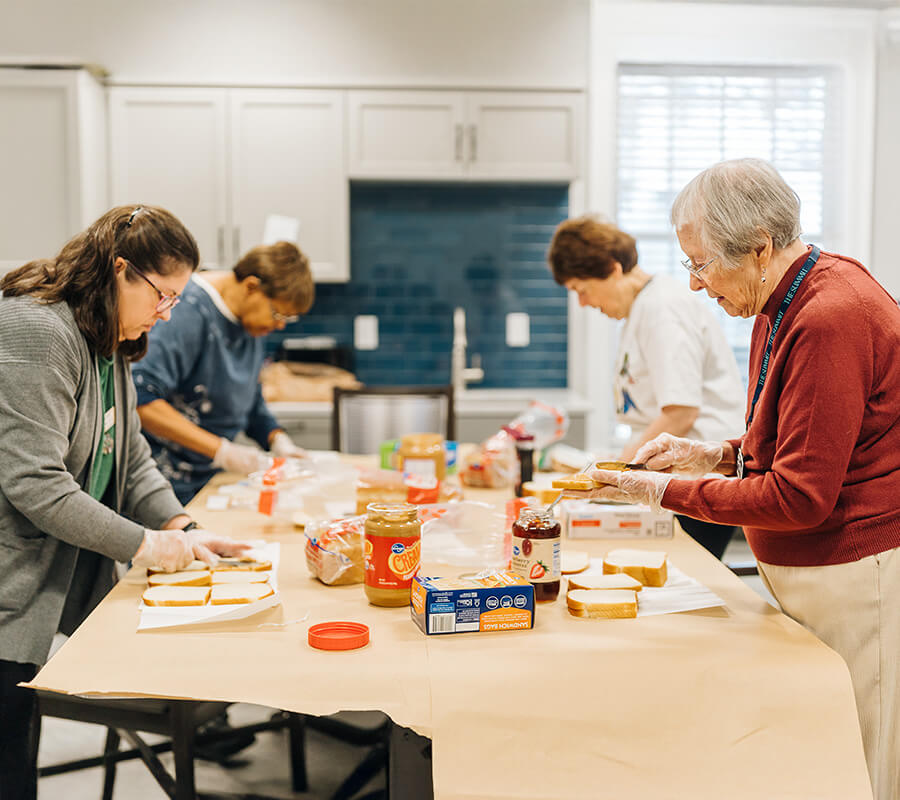 Seniors making sandwiches in a community kitchen for a volunteer project.