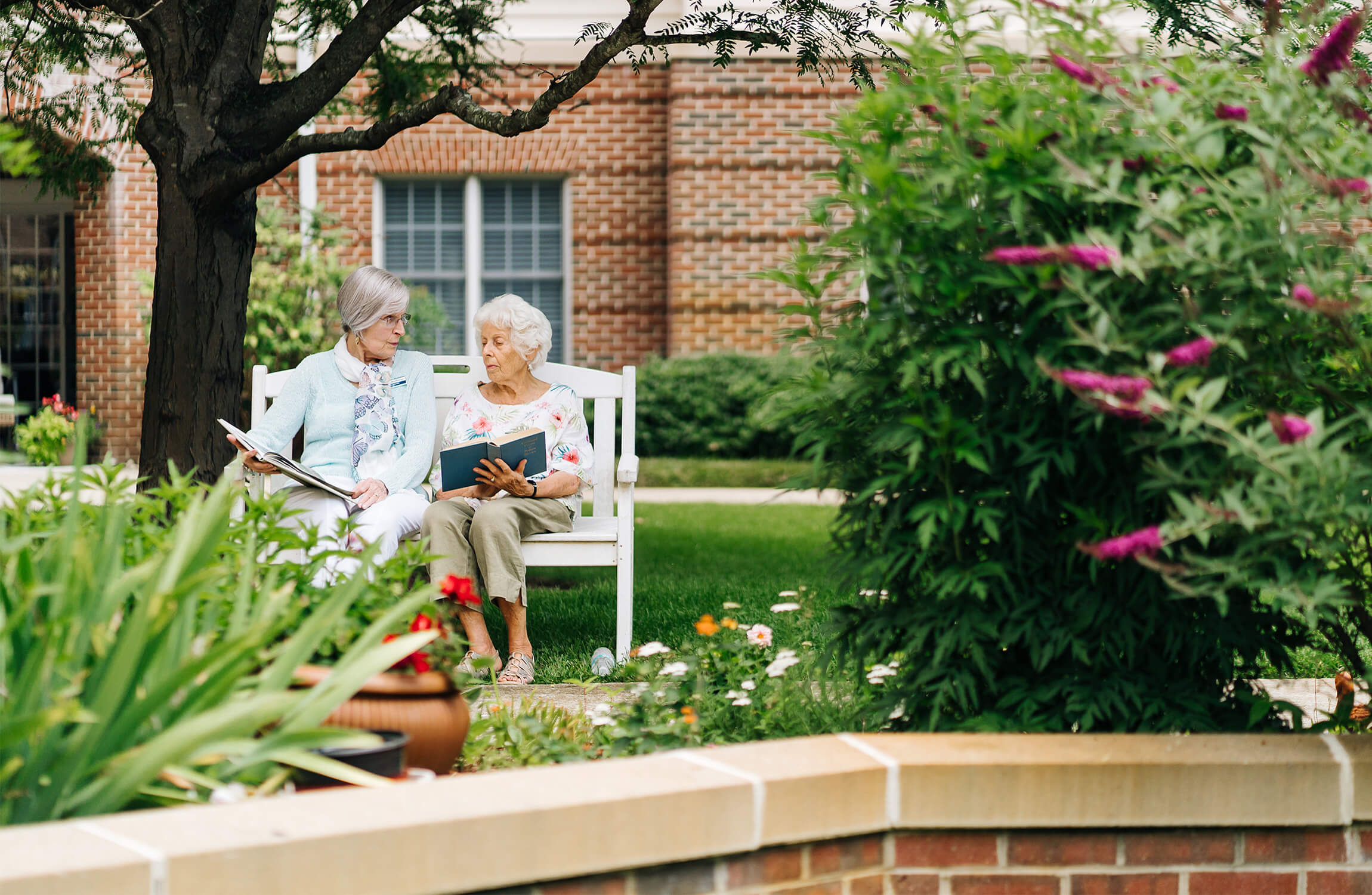 Serene Garden Reading Two women reading on a bench in a garden at a senior community complex.