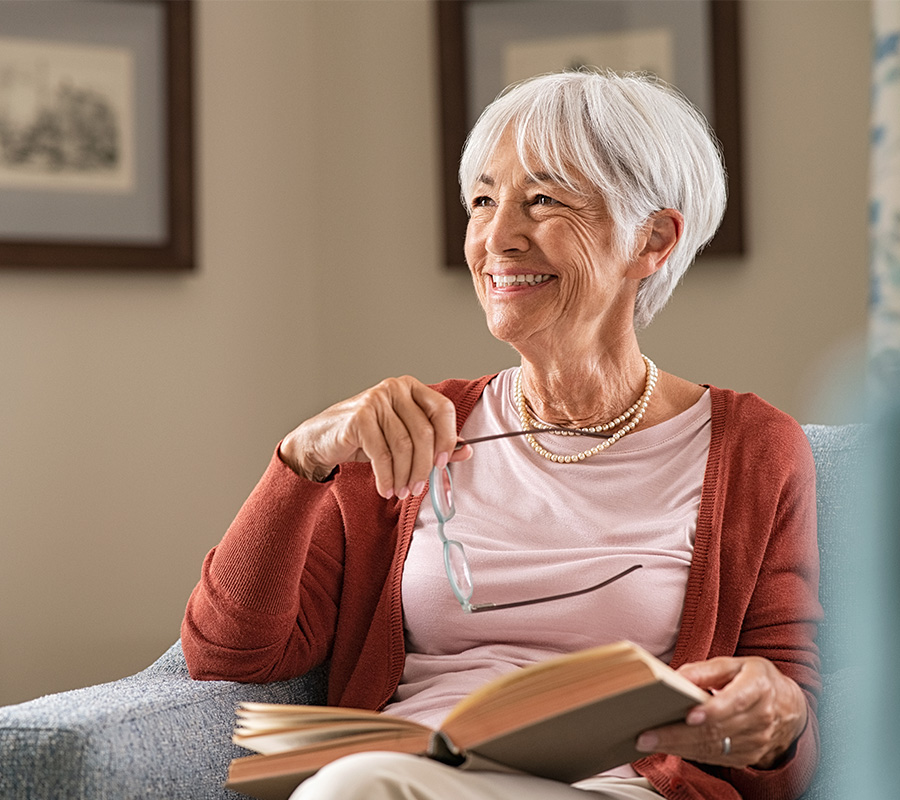 Senior reading on her couch and smiling