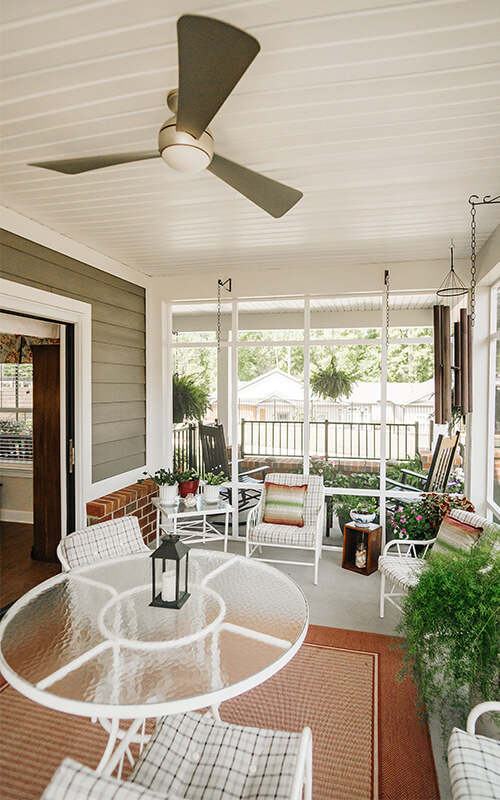 Sunroom with Garden View Charming sunroom with seating and garden view in a senior living community.