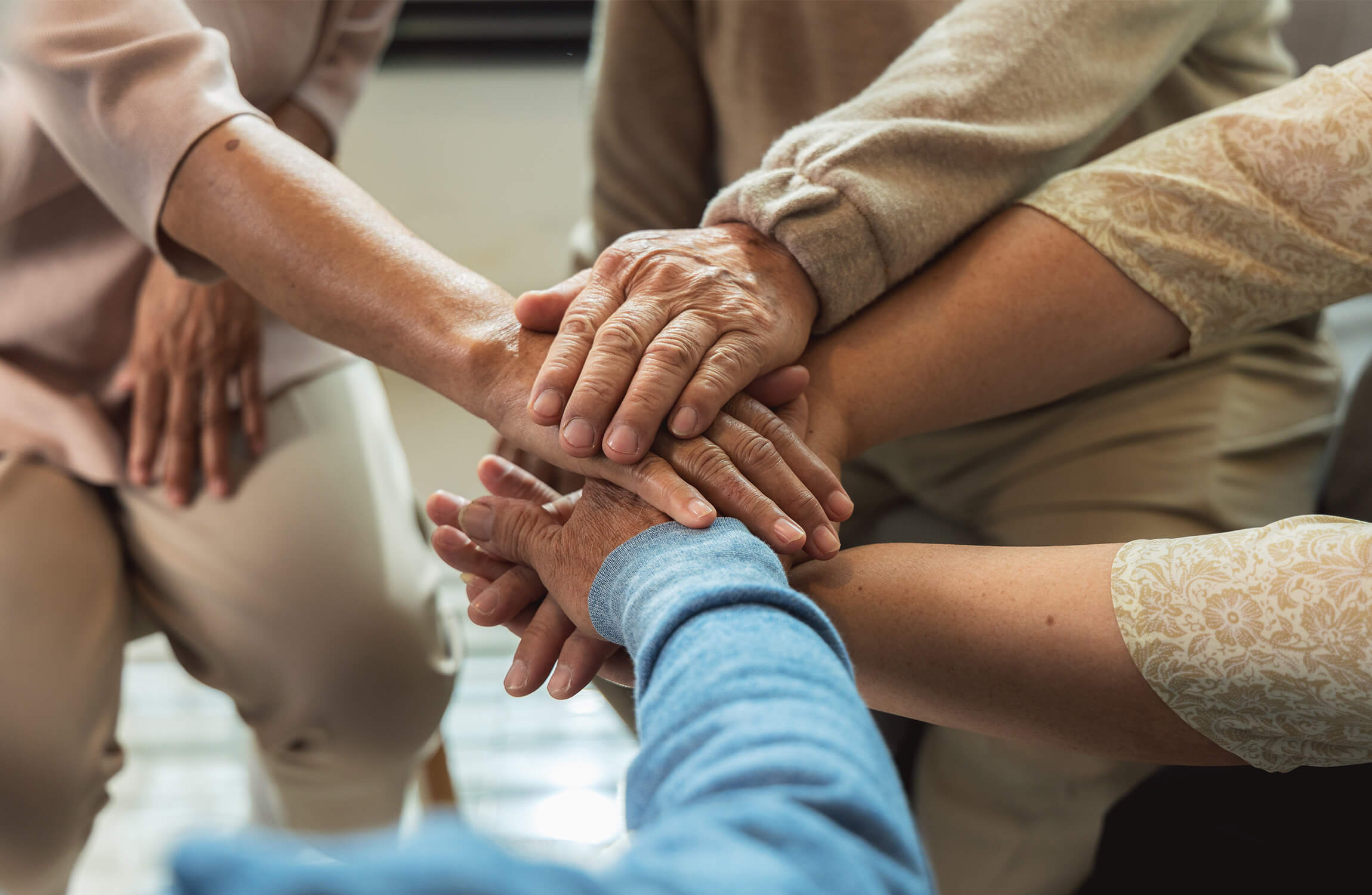 Close-up of joined hands symbolizing teamwork in a senior living environment.