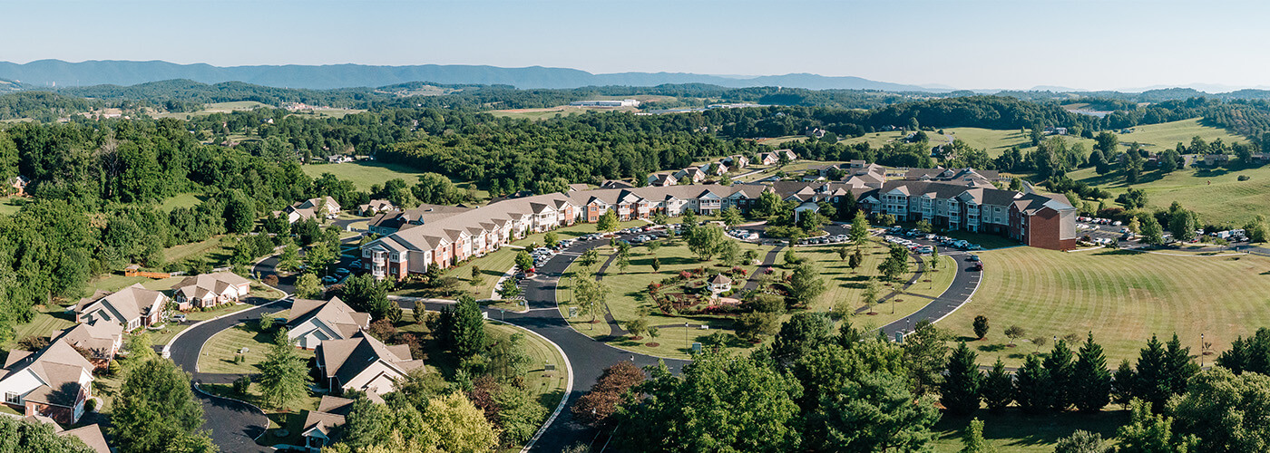 Aerial view of a sprawling community surrounded by lush greenery and distant mountains.