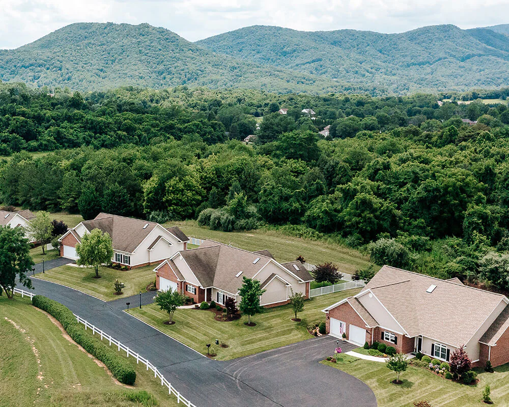 Aerial view of residential units surrounded by lush greenery and mountains.