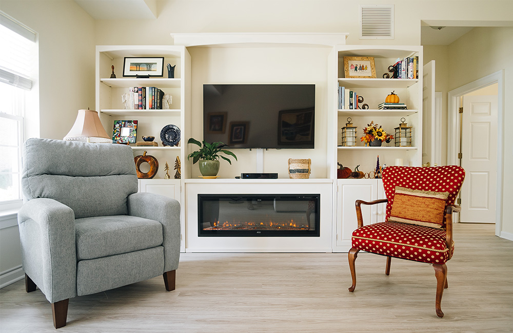 Cozy living room with armchairs and a fireplace in a senior living unit.