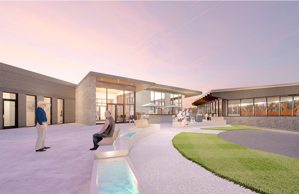 Modern senior living community courtyard during sunset with seating and landscaping.