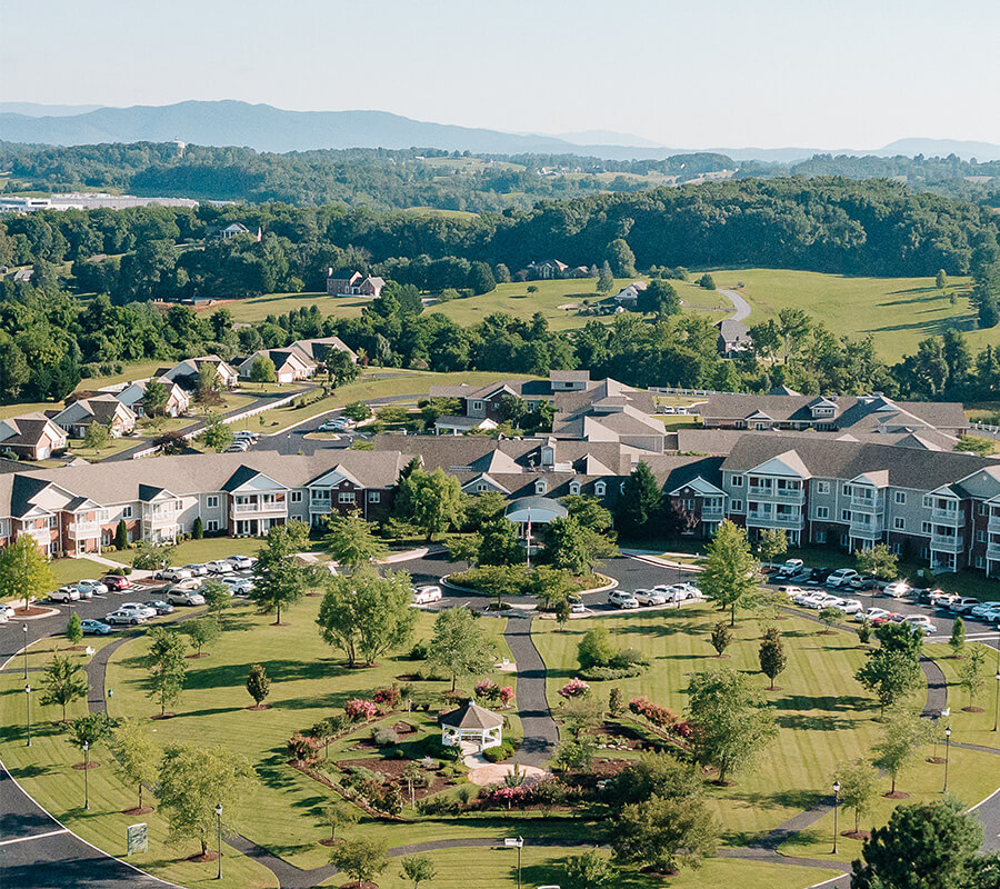 Aerial view of a senior living community with landscaped gardens and surrounding greenery.