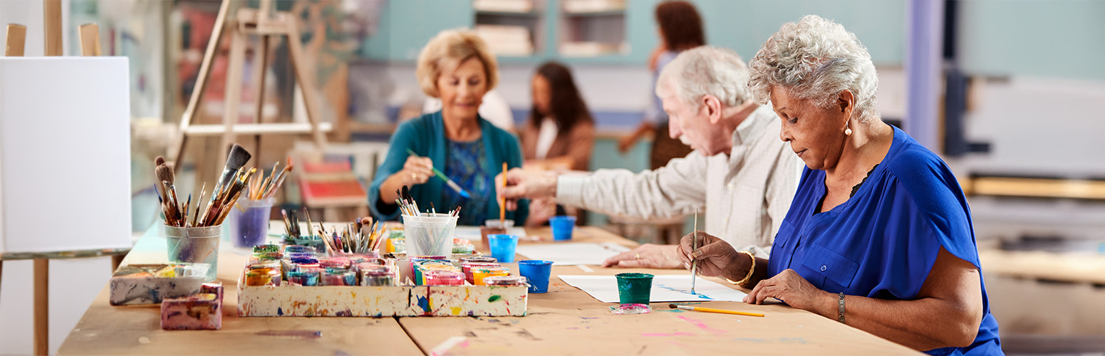 Seniors painting together in an art room filled with colorful paint supplies.