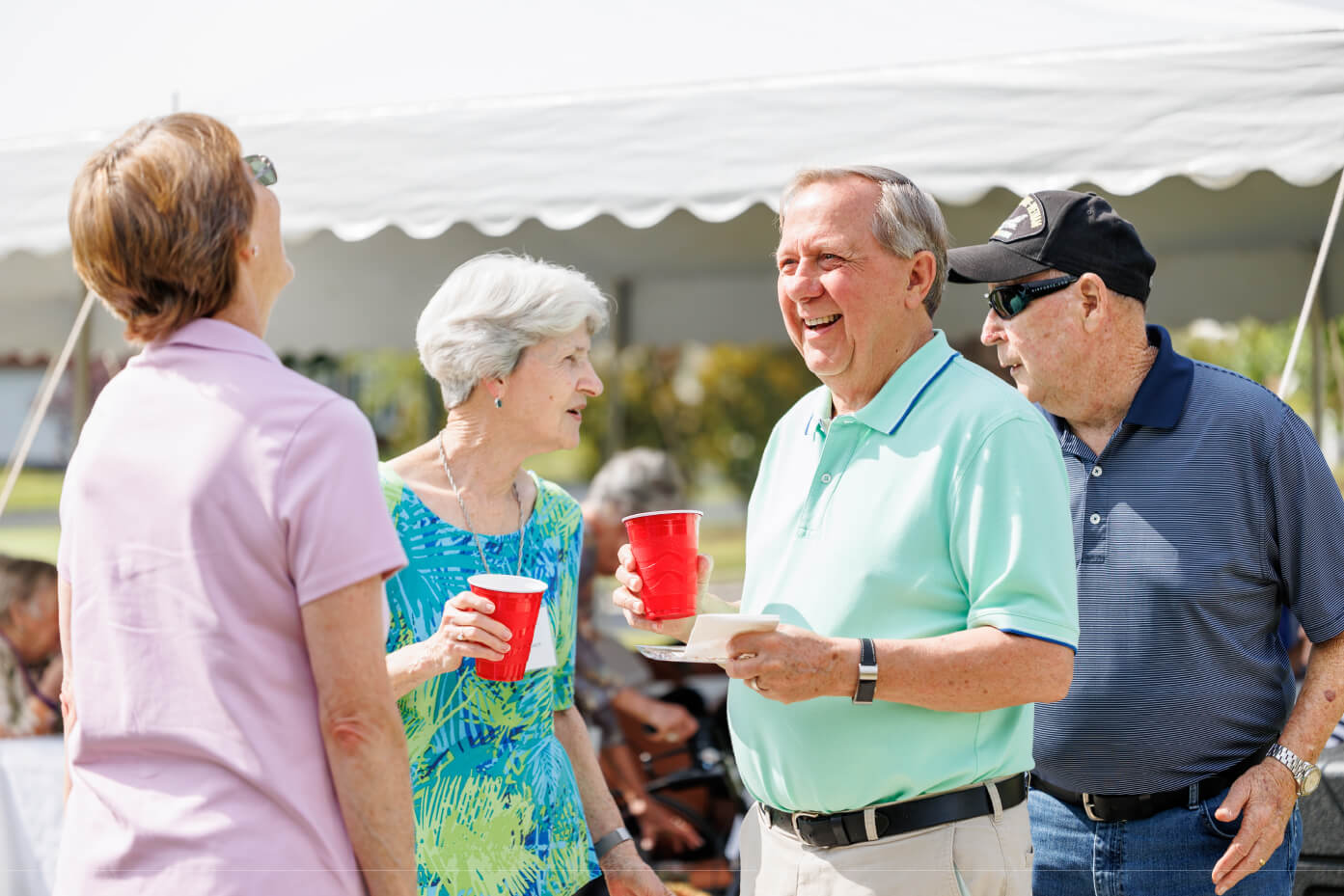 Senior friends chatting at an event with drinks