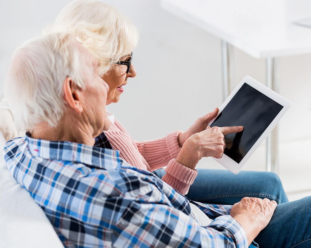 Senior couple using a tablet together while seated indoors.
