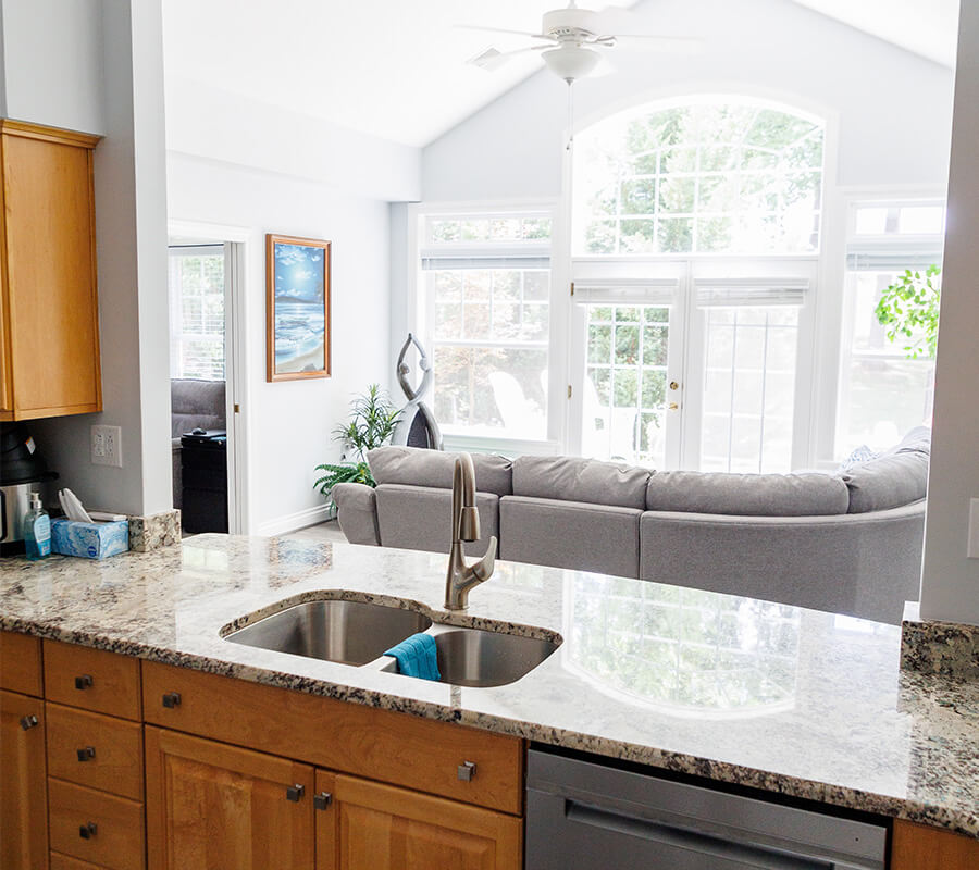 Open-concept kitchen and living area with granite countertops and large windows.