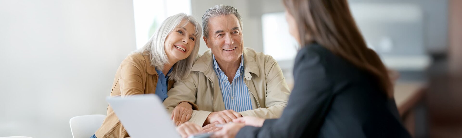Senior couple smiling at professional woman across from meeting table