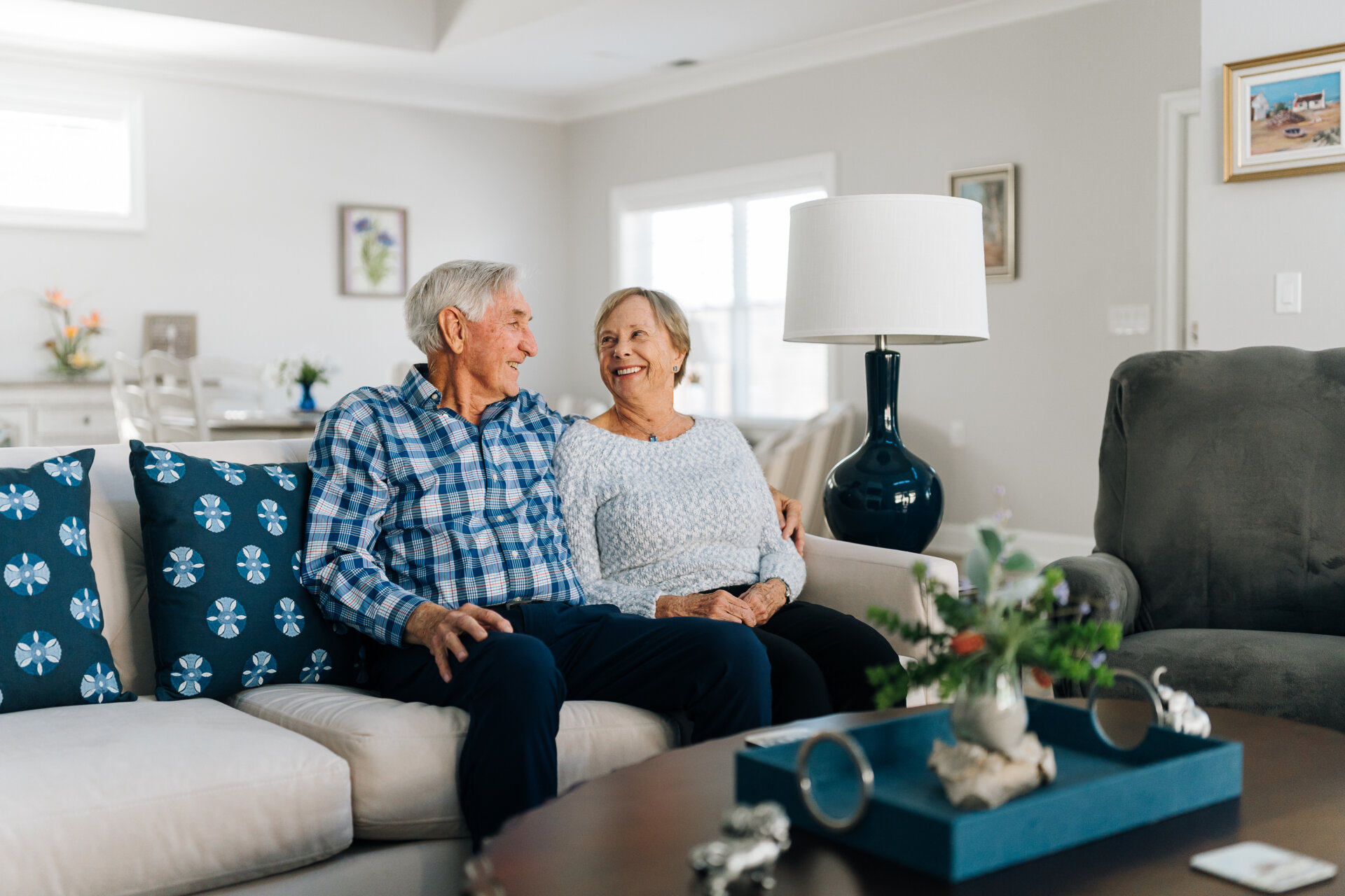 happy senior couple smiles at each other on the couch