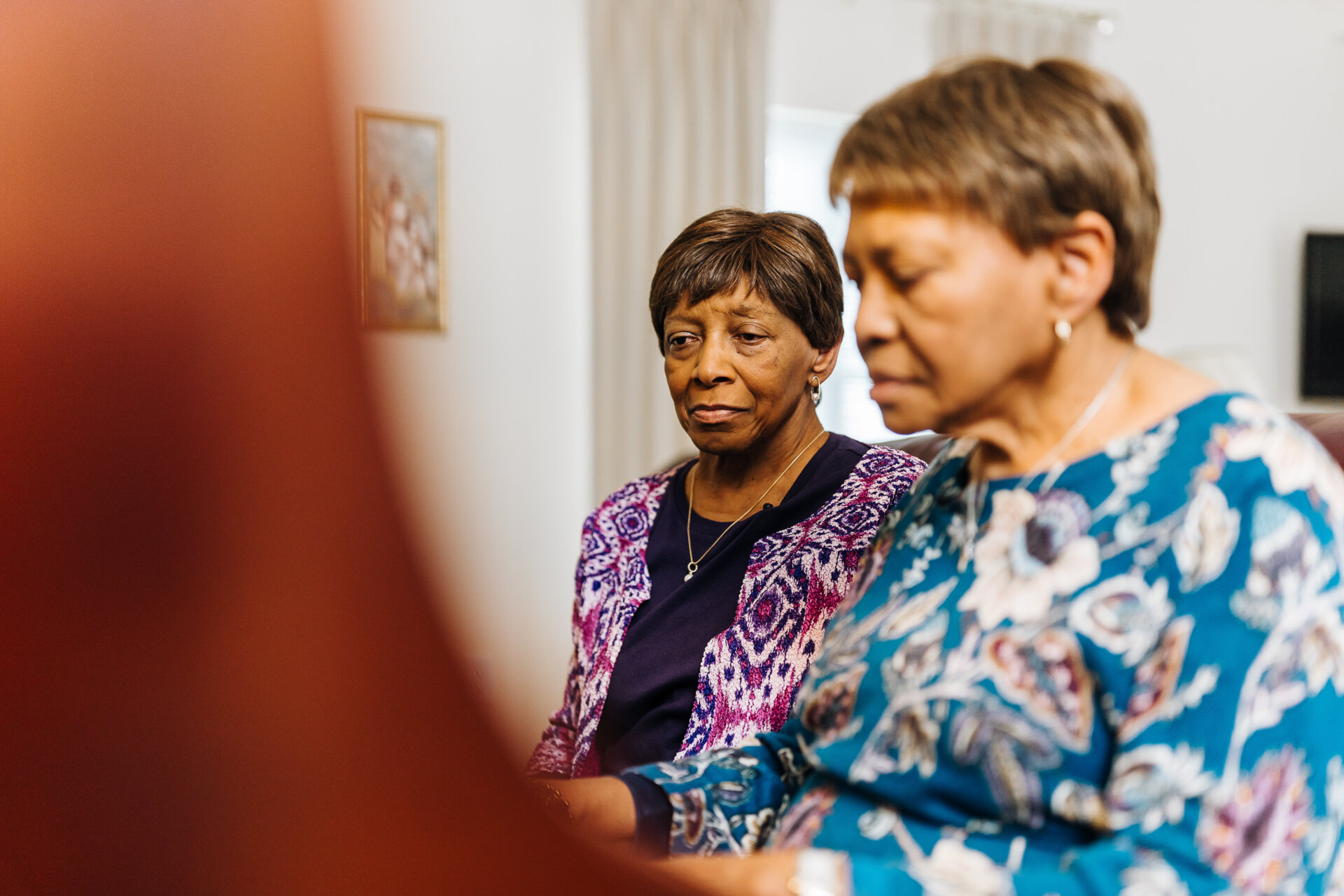 Senior woman playing the piano as another woman stands behind her and watches