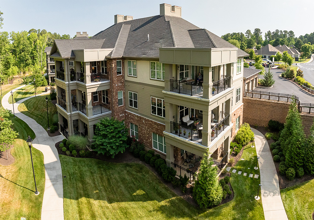 Aerial view of a senior living community building with landscaped paths and greenery.