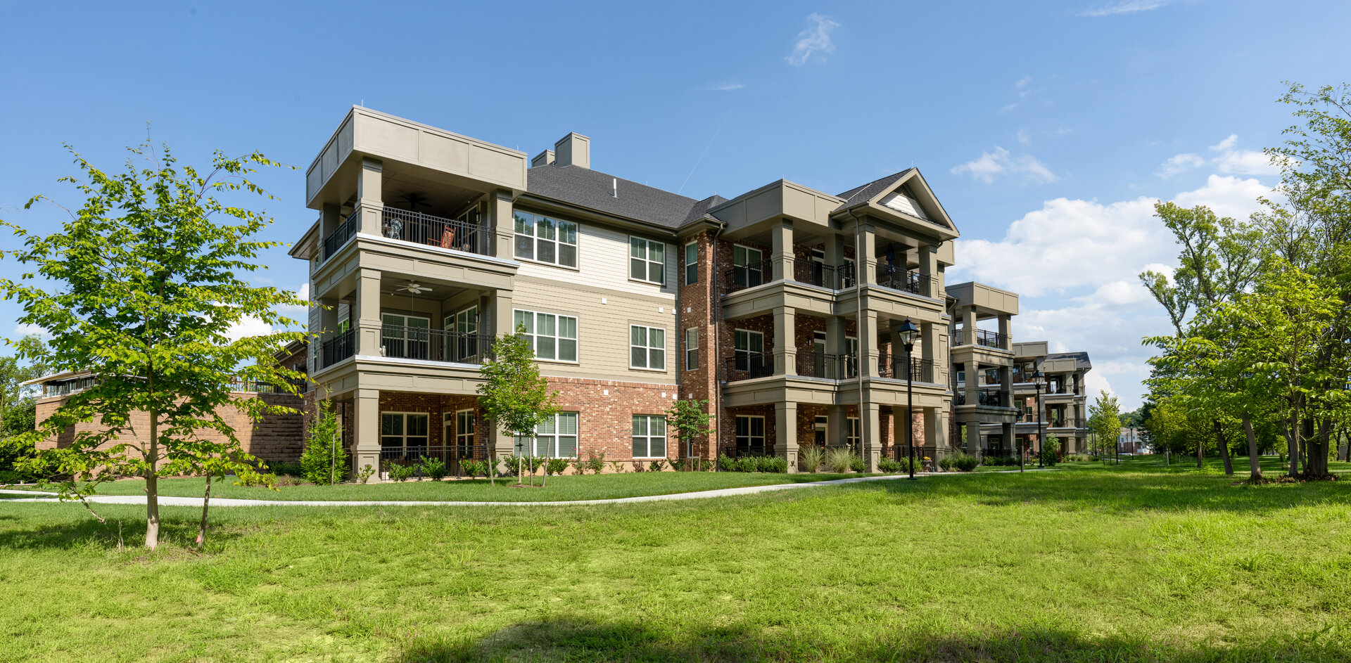 Exterior view of a modern senior living community building with lush green surroundings.