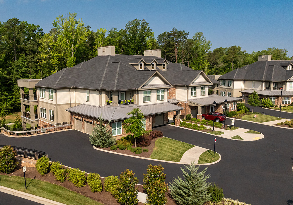 Aerial view of residential units surrounded by landscaped greenery and trees.