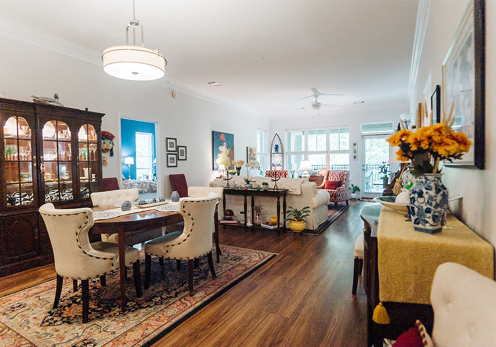 Elegant living area with dining table, sofa, and large windows in a senior community unit.
