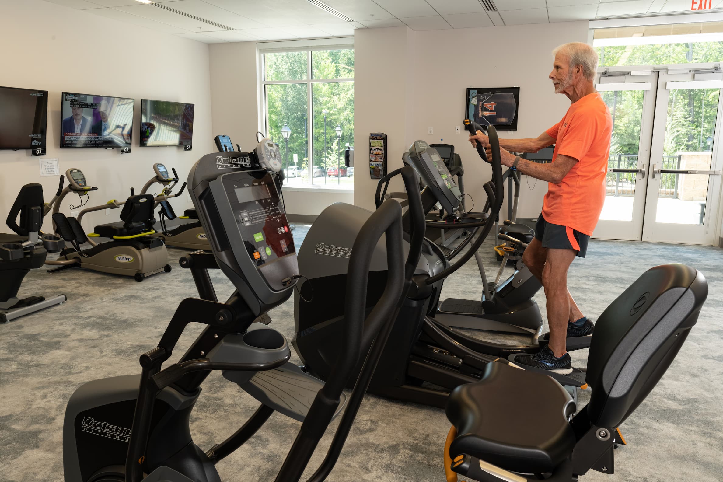 senior man using elliptical in senior living community gym