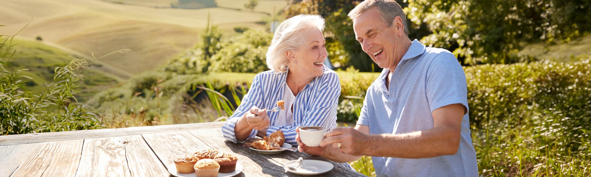 Two seniors enjoying breakfast and coffee outdoors