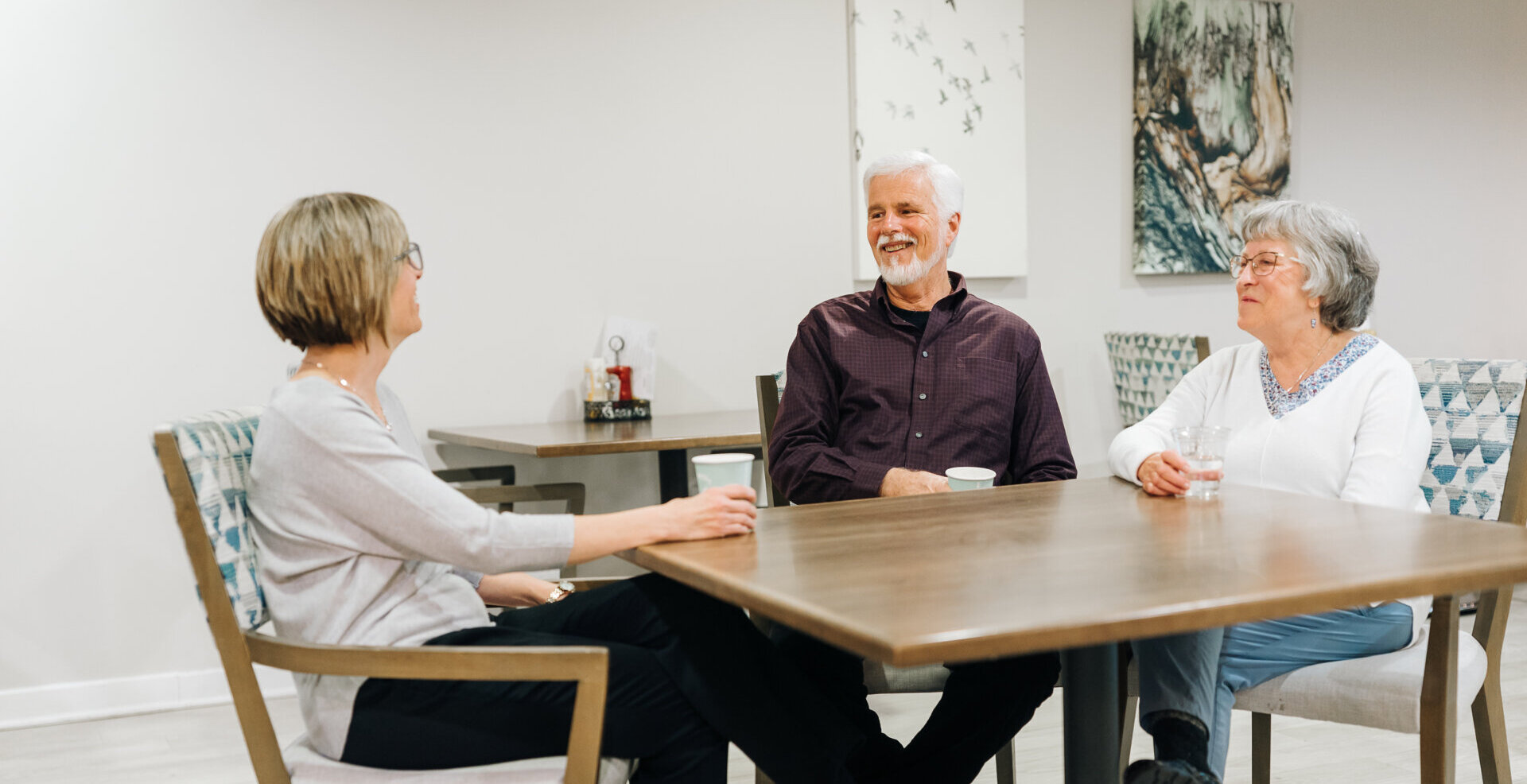 Senior couple and adult woman sitting around a table having a conversation