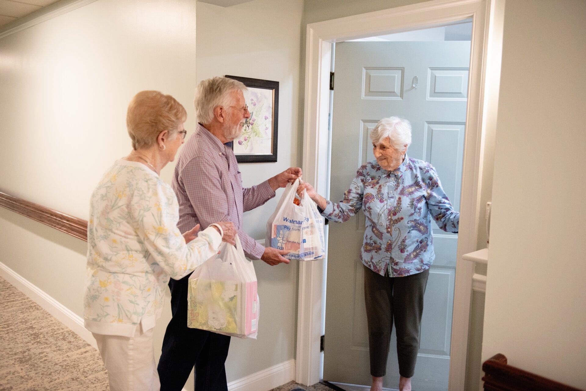 Senior woman receiving groceries from another pair of seniors
