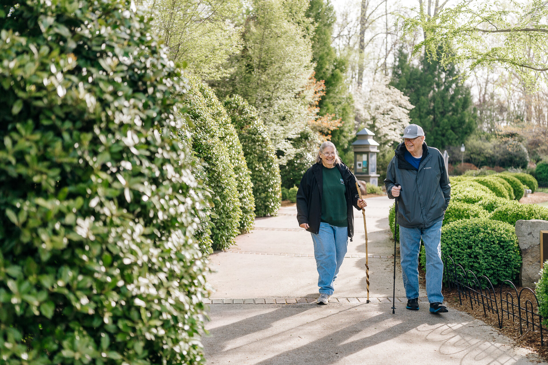 senior couple taking a stroll on pathway lined with greenery