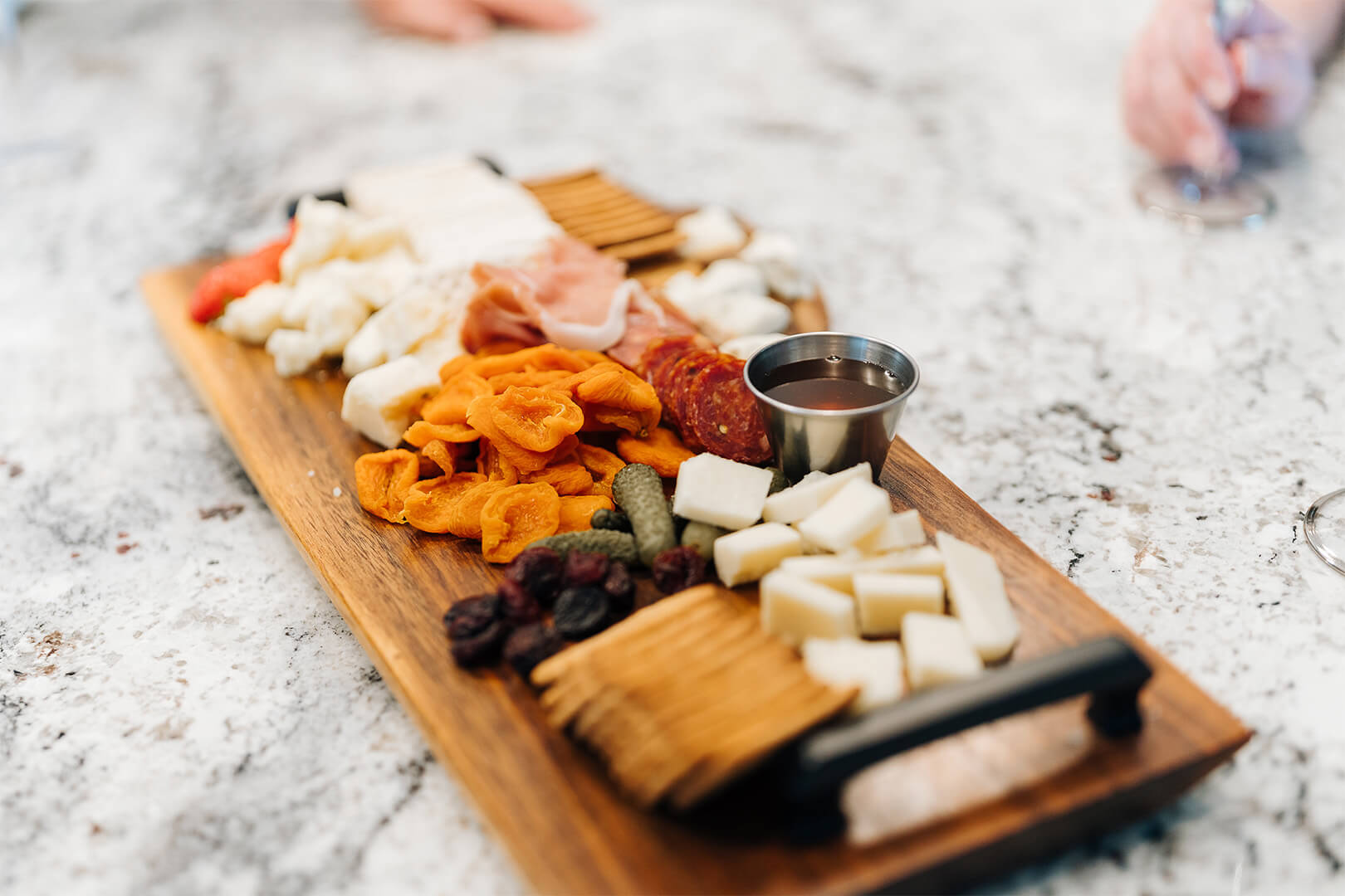 Charcuterie board with cheeses, meats, fruits, and crackers on a marble counter.