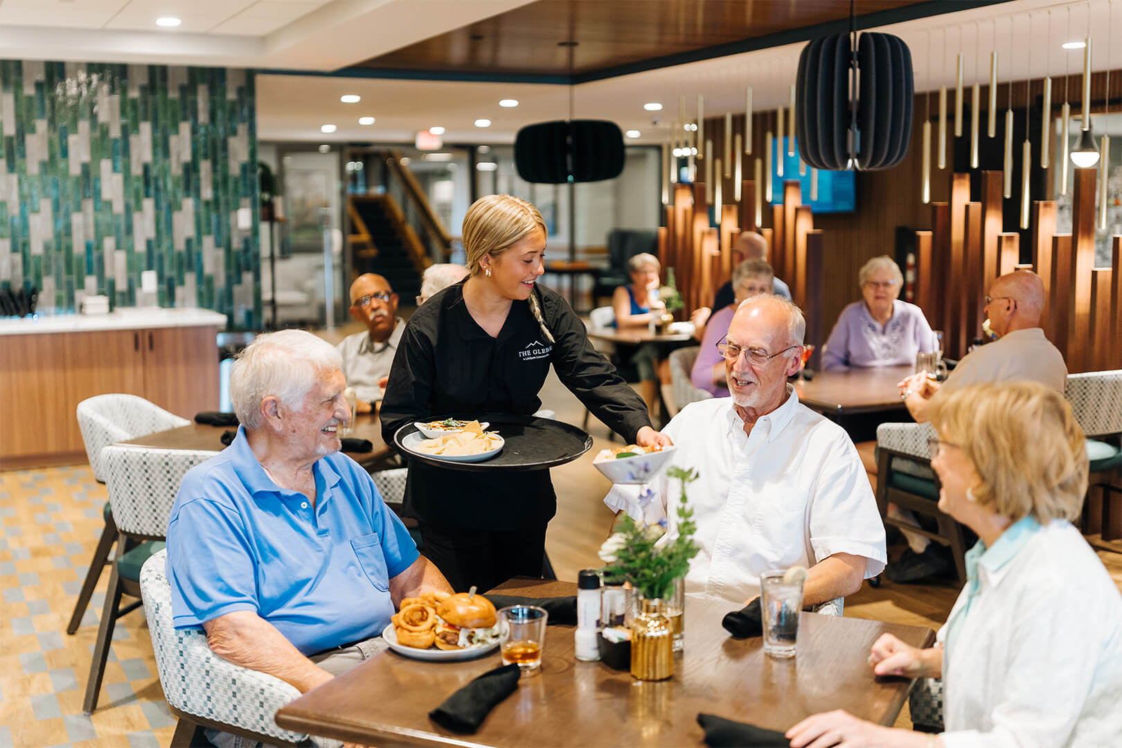 Residents enjoying a meal served by staff in a modern dining area.