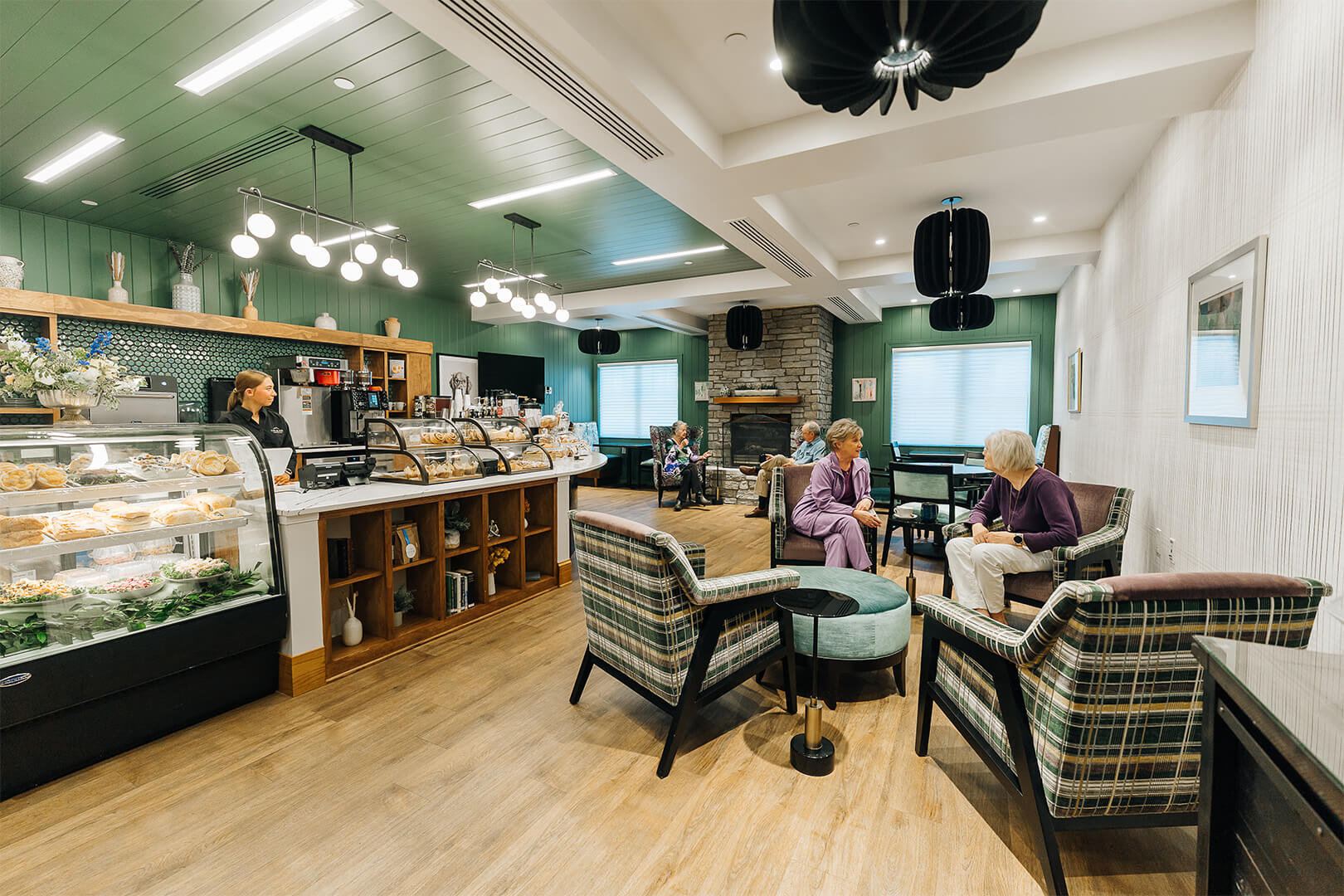 Residents enjoy conversation in a cozy cafe area within a senior living community.