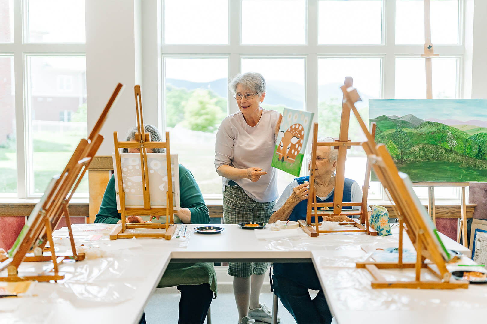 Seniors participate in a painting with an instructor in a bright studio.