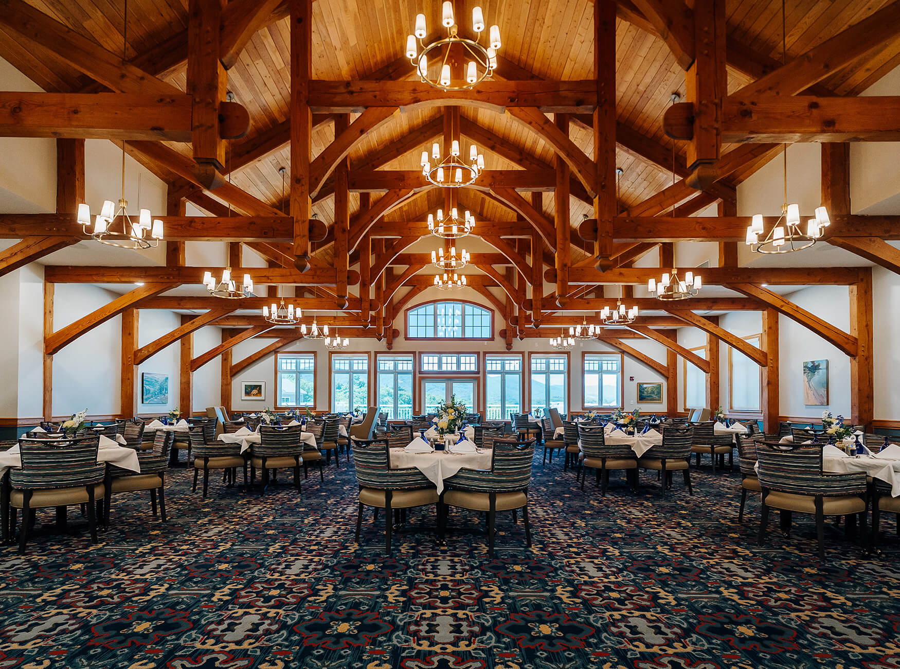 Spacious dining hall with wooden beams and elegant chandeliers in a senior community.
